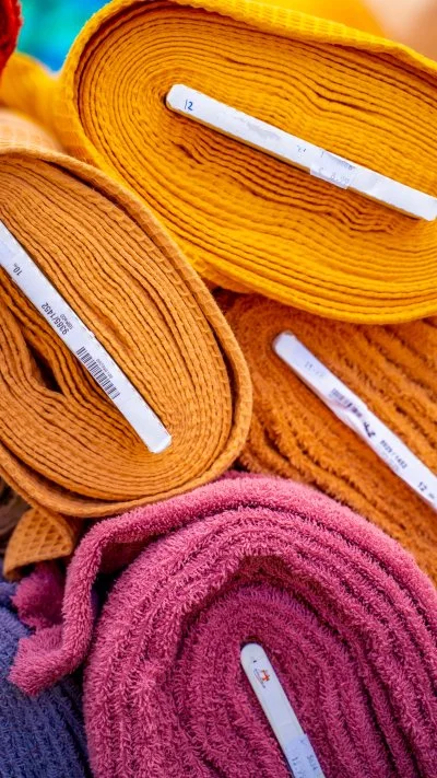 Gestapelte Cord-Stoffrollen in Gelb, Orange und Rosa